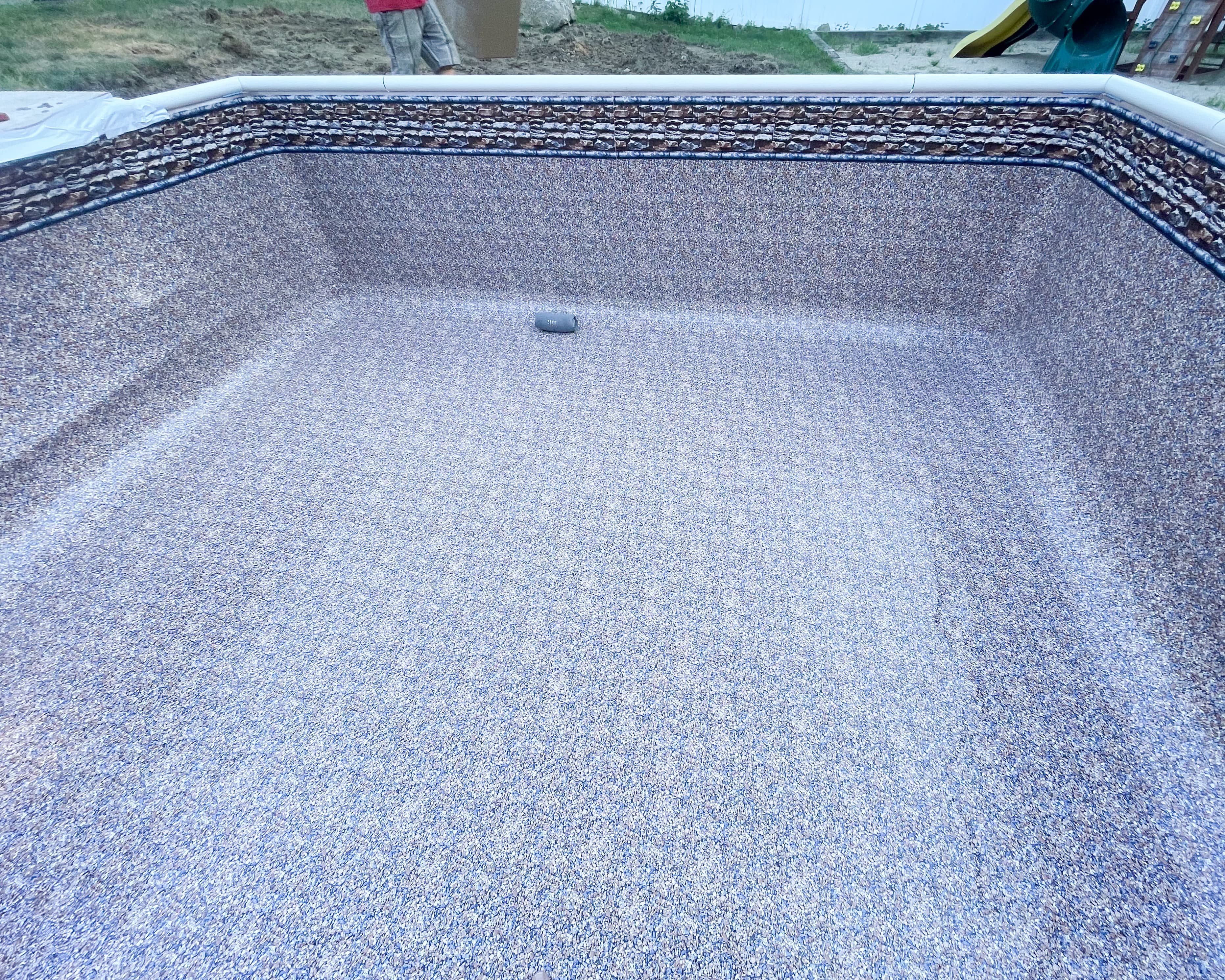 Empty in-ground pool with new liner installation showing smooth light blue surface and clean finish