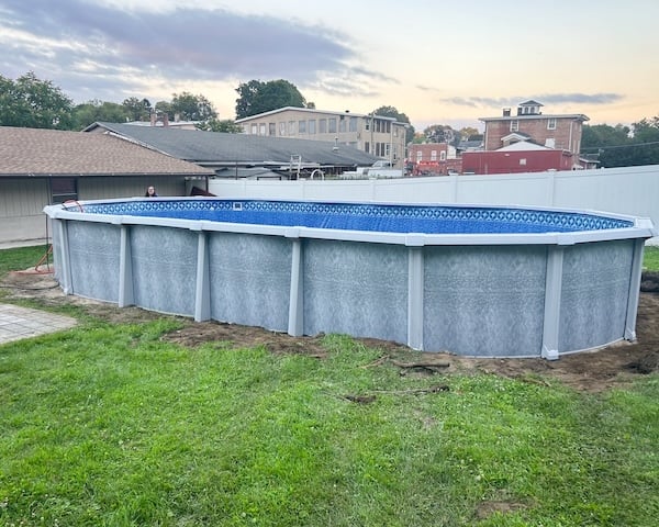 Oval above-ground pool with blue liner and grey walls installed in backyard